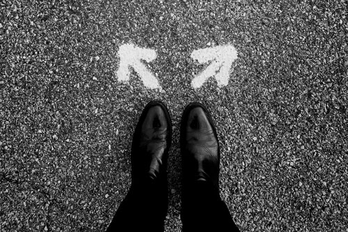 Person looking at arrows on the ground and deciding which direction to choose. Person looking at arrows on the ground and deciding which direction to choose.