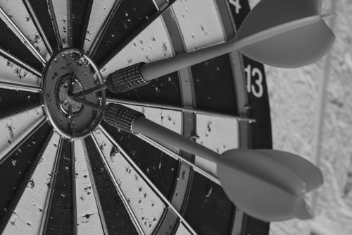 Photo of a dartboard with darts having hit the target.